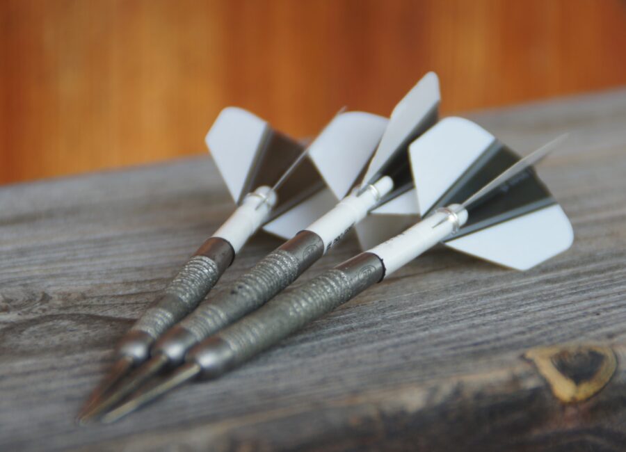 Three steel-tip darts on a wooden surface